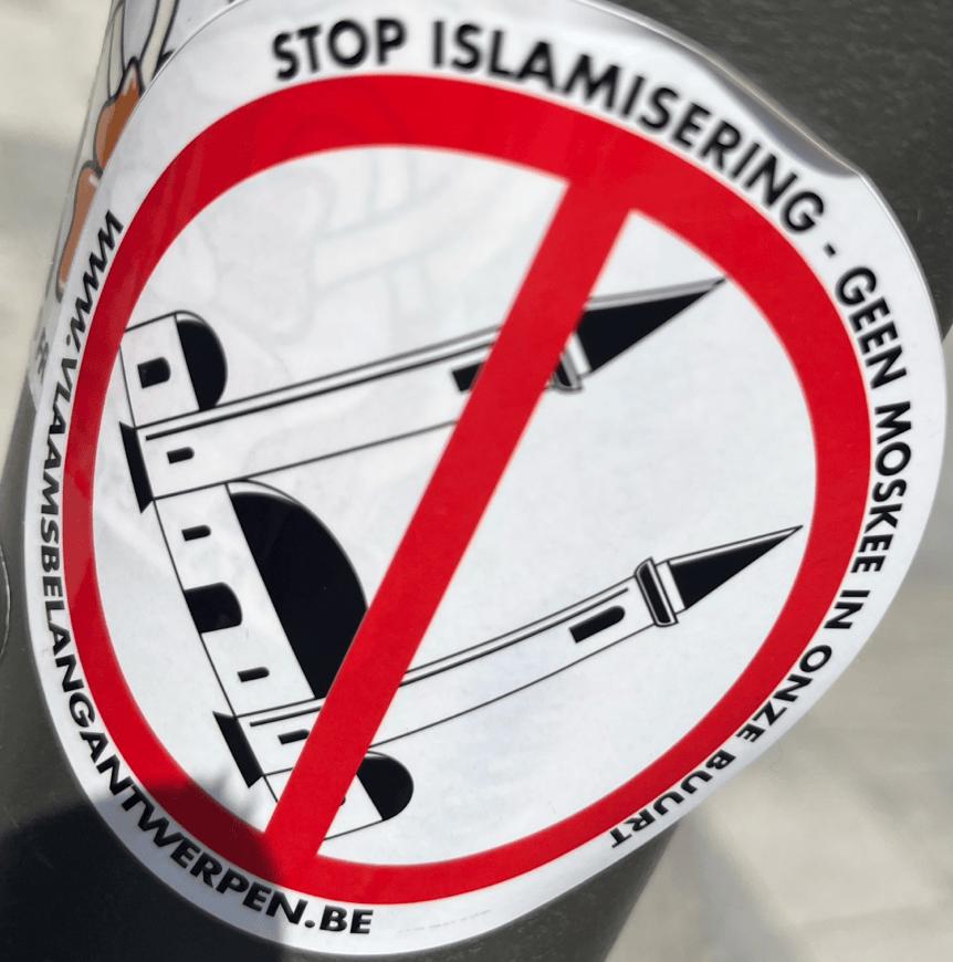A cartoon of a mosque with a forbidden sign over it. It reads "Stop islamisering - Geen moskee in onze buurt" on the top, with "www.vlaamsbelangantwerpen.be" on the bottom